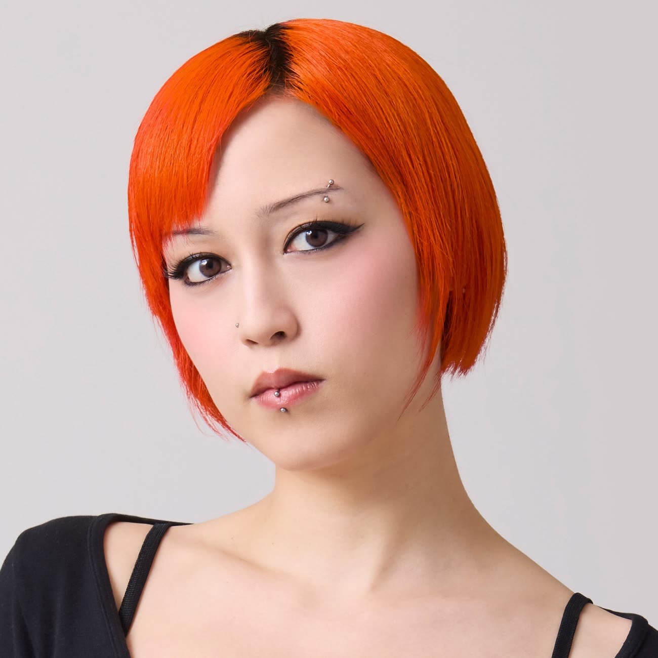 A model with a sleek neon orange bob, wearing Good Dye Young's Riot shade